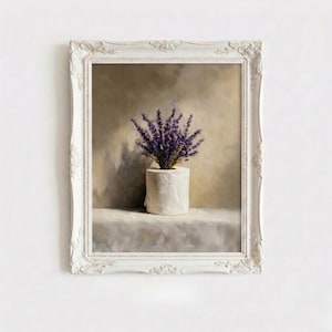 Puede incluir: Una obra de arte enmarcada que presenta un rollo de papel higiénico blanco con un ramo de lavanda púrpura. La obra de arte está ambientada sobre un fondo neutro y enmarcada en un marco blanco ornamentado, creando una naturaleza muerta única.
