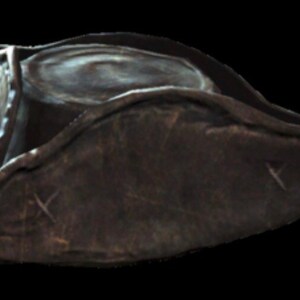 May include: A dark brown leather pirate hat with a wide brim and a slightly pointed crown. The hat has a worn and weathered look, with visible stitching and creases.