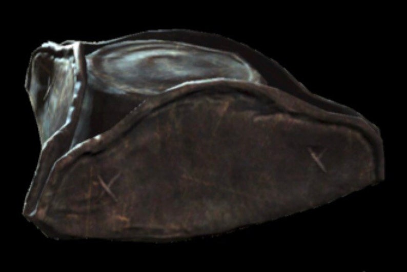 May include: A dark brown leather pirate hat with a wide brim and a slightly pointed crown. The hat has a worn and weathered look, with visible stitching and creases.