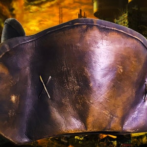 May include: A brown leather pirate hat with a stitched X on the front. The hat is worn and has a distressed look.