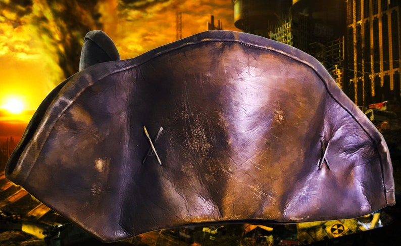 May include: A brown leather pirate hat with a stitched X on the front. The hat is worn and has a distressed look.