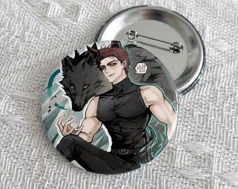 May include: A circular pinback button featuring an anime-style illustration of a person with short reddish-brown hair wearing a black sleeveless top, positioned next to a large black wolf. A small speech bubble with a paw print icon is visible.