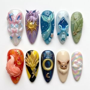 May include: A set of ten sculpted nail art designs. Each nail features a different design, including a mermaid tail, a fox, and various cartoon characters. The nails are painted in a variety of colors, including blue, orange, and purple.