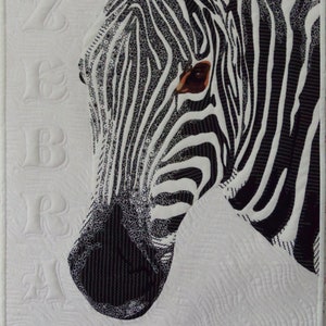 May include: Close-up of a black and white zebra's face. The zebra's stripes are detailed and the eye is visible. The background is white with a quilted pattern.