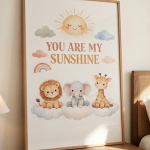 May include: A framed print featuring a smiling sun, clouds, a rainbow, and three cartoon animals: a lion, an elephant, and a giraffe. The text "YOU ARE MY SUNSHINE" is displayed in a soft, warm color palette.