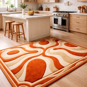May include: A rectangular area rug with a retro design. The rug features a pattern of orange, cream, and beige swirling shapes. The rug is placed on a hardwood floor in a kitchen setting.