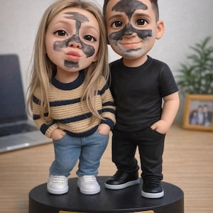 May include: A figurine of a couple with charcoal face masks. The woman wears a striped sweater, jeans, and white sneakers. The man is in a black shirt, pants, and shoes. They stand on a black base with a gold nameplate.