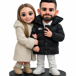 May include: A figurine of a couple, standing close together on a black base. The woman wears a cream-colored coat with a fur-lined hood and boots. The man wears a black puffer jacket and white sneakers. The figurine is a cartoon-like representation.