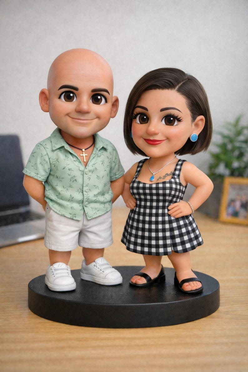 May include: A figurine set of a couple standing on a black base. The man wears a green shirt, white shorts, and sneakers. The woman wears a black and white checkered dress and black sandals. Both figures have large eyes and are smiling.