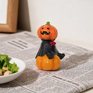 Schattig pompoenfiguurtje in een zwarte cape, grappig Halloween-decoratiefiguurtje voor op een plank, klein bureauornament van hars, griezelige herfstdecoratie, uniek Halloween-cadeau.