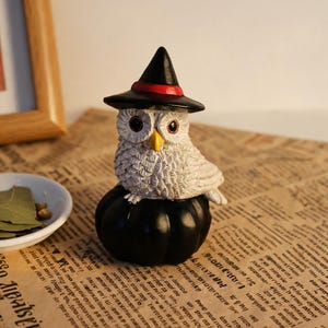 Handgemaakte uilfiguur op een zwarte pompoen, schattige Halloween-uil met heksenhoedje, klein bureaubeeldje van hars, een leuk herfstcadeau van Whimsigoth.