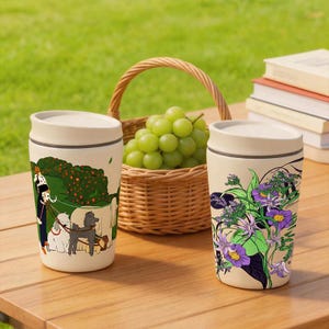 May include: Two off-white cylindrical travel mugs with lids. One mug features a colorful illustration of a person walking three dogs in a park. The other mug displays a vibrant botanical print with purple flowers and green leaves on a cream background.