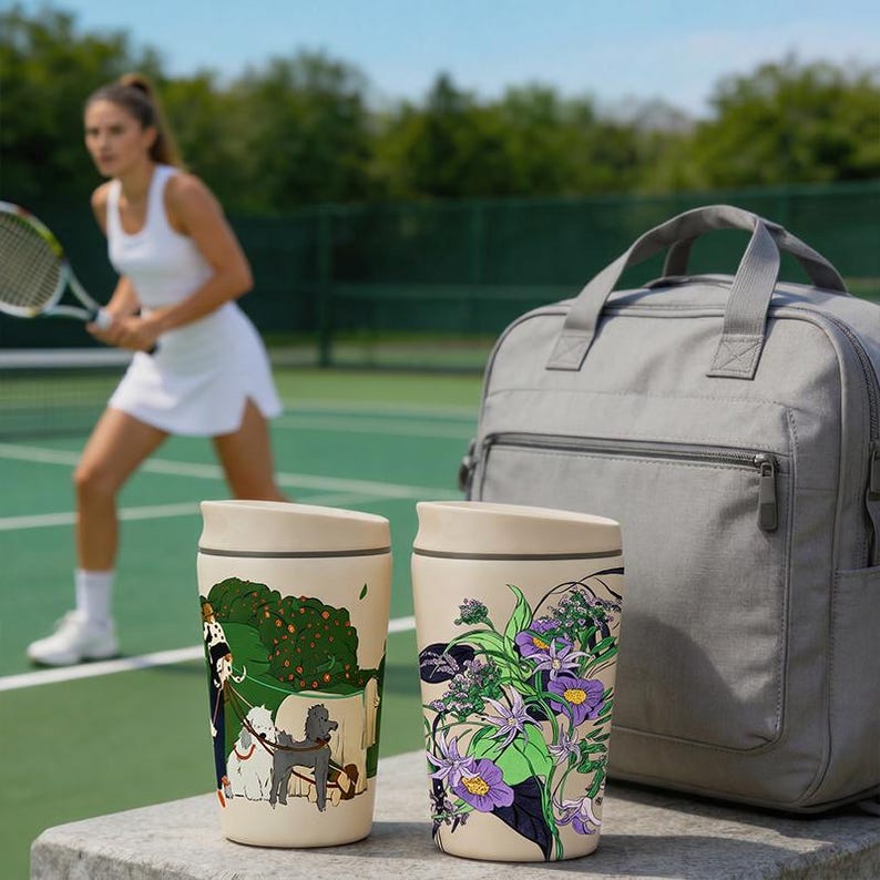 May include: Two cream-colored travel mugs with lids. The left mug features a graphic of a person walking three dogs in a park. The right mug displays a botanical illustration of purple flowers and green leaves. A gray backpack sits behind the mugs.