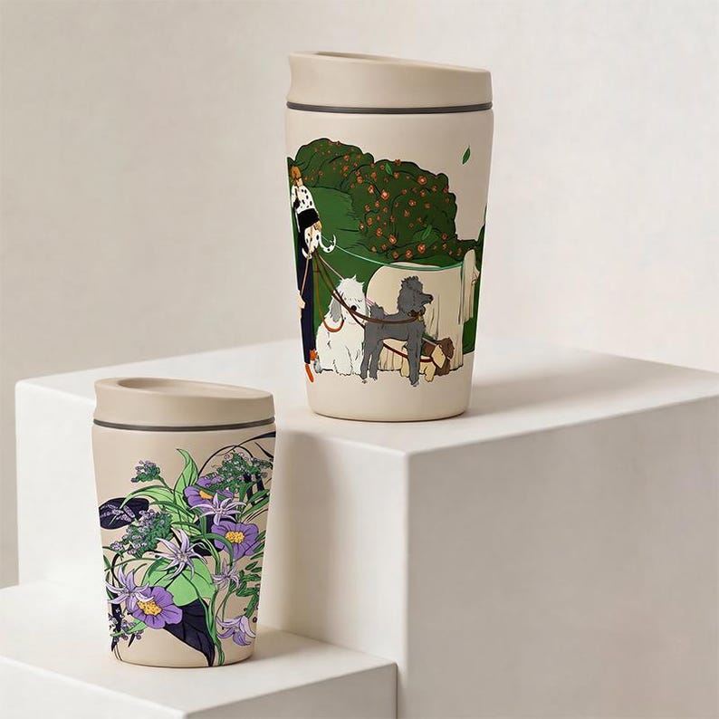 May include: Two beige travel mugs with lids. The taller mug features a graphic illustration of a person walking several dogs in a green park. The shorter mug displays a detailed botanical print with purple flowers, green leaves, and dark accents.