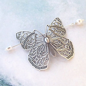 May include: Silver butterfly hair comb with a pearl accent. The butterfly is intricately detailed with a filigree design.