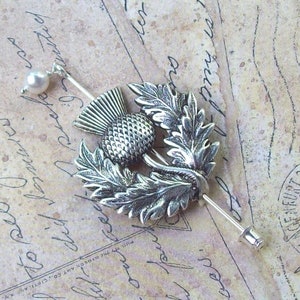 May include: Silver thistle brooch with a pearl accent. The thistle is a traditional Scottish symbol.