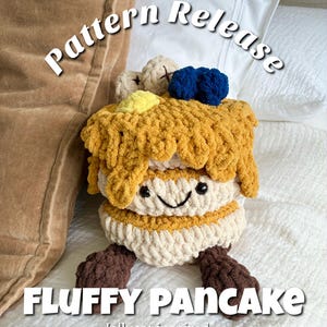 May include: A handmade, plush, fluffy pancake toy with a smiling face, brown feet, and various toppings. The text "Pattern Release" and "Fluffy Pancake" are displayed on the image, along with "Jellycat inspired".