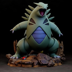 May include: A green and blue Tyranitar figure with an open mouth, standing on a rocky base. The figure has sharp spikes and a blue belly. A red and white Poké Ball sits on the base.