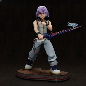 Puede incluir: Una figura de un personaje con cabello morado, que lleva un chaleco gris, pantalones azules y zapatillas blancas con cordones morados. El personaje sostiene una gran espada azul y roja. La figura está sobre una base de madera con borde rojo.