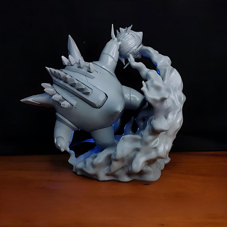 May include: A gray figurine of a stylized creature with a spiky back and a round head, seemingly emerging from a cloud-like structure. The figurine is on a wooden surface with a dark background, and blue light emanates from the base.