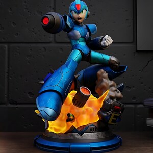 以下が含まれることがあります： 赤く光るキャノンアームを持つ、青とティールのアクションフィギュアのダイナミックな置物。フィギュアは、オレンジ色の炎と煙の効果があるベースの上にあります。ベースは青色で、黒と黄色の文字「E」が付いています。