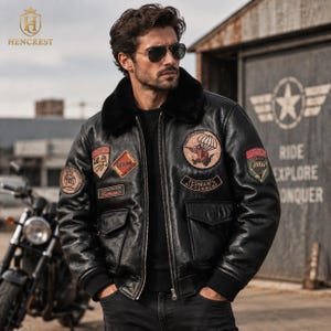 May include: A black leather bomber jacket featuring a black faux fur collar, a front zipper closure, and multiple embroidered patches including a circular Tedman's Air Command emblem, a parachute graphic, and various rectangular text labels.