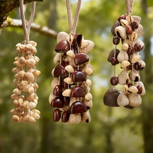 May include: Three decorative hanging ornaments made from natural materials. The ornaments are suspended from a tree branch by beige rope loops. The ornaments feature a variety of shapes and colors, including light beige, brown, and dark brown.