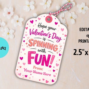 May include: A Valentine's Day gift tag with a pink and white design. The tag has a pink string and features the text "Hope your Valentine's Day is Spinning with FUN!" and measures 2.5" x 3.5".