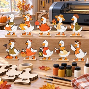 Puede incluir: Un conjunto de diez figuras de patos de madera con varios accesorios de temática otoñal como calabazas, bufandas, sombreros y linternas. La colección incluye figuras de madera sin pintar, pequeños botes de pintura y pinceles para decorar.