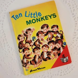 May include: A children's book titled Ten Little Monkeys with a bright yellow cover featuring ten illustrated brown monkeys. The cover includes the text Ten Little Monkeys, the publisher name Brown Watson, and a Start-Right Elf Book logo.
