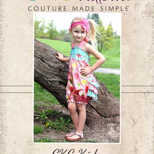 May include: A young girl wearing a pink and blue floral dress with a ruffle hem, standing in front of a tree. The dress has a gathered bodice and a bubble hem. The girl is wearing a pink headband with a flower. The image is from CKC Patterns, Couture Made Simple, CKC Kids.