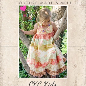 May include: A young girl wearing a multi-coloured floral dress with a brown and white polka dot trim. The dress has a layered design with a ruffled hem. The girl is standing in a tree with a green leafy background. The text "CKC Patterns Couture Made Simple" is at the top of the image and "CKC Kids" is at the bottom of the image.