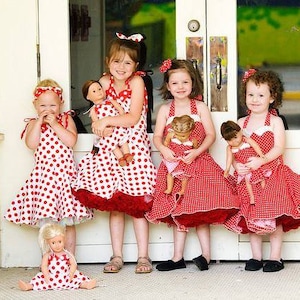 Könnte beinhalten: Fünf Mädchen in rot-weißen Polka-Dot-Kleidern stehen vor einer weißen Tür. Jedes Mädchen hält eine Puppe, die in einem ähnlichen Stil gekleidet ist. Die Puppen tragen ebenfalls rot-weiße Polka-Dot-Kleider.