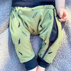 May include: Green baby pants with a black lightning bolt pattern and a black zipper down the side.