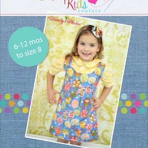 May include: A blue and white dress with a floral print and a yellow collar. The dress is handmade and has the text "Create Kids Couture" and "Dainty Photos" on it. The dress is for a child and is sized 6-12 months to size 8.