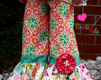 May include: A pair of white, green and orange patterned trousers with a pink flower accent. The trousers have a ruffled hem and a turquoise waistband. The trousers are made by Create Kids Couture.