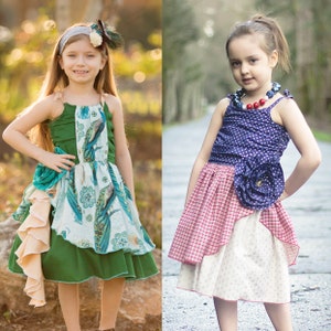 May include: Two young girls wearing colorful dresses. The girl on the left is wearing a green dress with a blue and white patterned overlay and a floral headband. The girl on the right is wearing a blue and white polka dot dress with a red and white checkered overlay and a red beaded necklace.