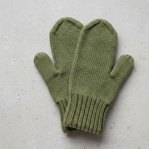 May include: A pair of olive green knitted mittens. The mittens have a ribbed cuff and a thumb. The knitted texture is visible throughout the mittens. The mittens are made of a soft, warm material.