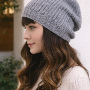 May include: A gray knit beanie with a ribbed design. The hat is made of a soft material and has a slouchy fit. The beanie is a neutral color and can be worn with many outfits. The hat is a winter accessory.