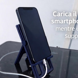Può includere: Uno smartphone blu navy è tenuto in posizione verticale da un supporto abbinato, collegato a un cavo di ricarica bianco. Il supporto è progettato per tenere il telefono. Il testo nell'immagine recita: "Carica il tuo smartphone mentre è sul supporto."