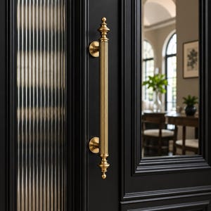 Pode incluir: Uma porta preta fosca com um painel de vidro canelado vertical e um puxador cilíndrico longo de latão com acabamentos decorativos no topo e na base. A porta possui uma moldura profunda e uma inserção de vidro reflexivo.