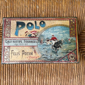May include: A rectangular vintage metal tin featuring a colorful illustration of a polo match. The text reads Polo, Gaufrettes Fourrées au Praliné, and Félix Potin Paris. The design includes decorative red and gold borders with ornate patterns.