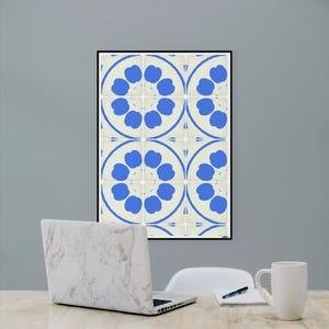 Peut inclure: Une impression d'art murale rectangulaire présentant un motif répétitif de cercles bleus sur un fond crème clair, encadrée par un cadre noir fin. Le design se compose de formes florales symétriques disposées en une grille de douze carreaux.