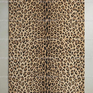 以下が含まれることがあります： ヒョウ柄の長方形ラグ。ラグは、濃い茶色と黒の斑点のあるタン色の背景を特徴とし、自然なアニマルプリントのデザインを作り出しています。ラグはおそらく織物素材で作られています。