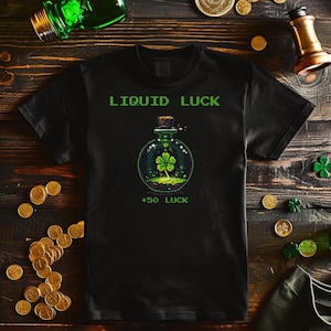 May include: Black t-shirt featuring the text "LIQUID LUCK" in a green pixelated font. A green potion bottle graphic with a four-leaf clover is centered below the text. The text "+50 LUCK" is below the bottle.