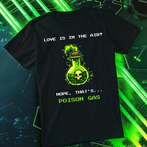 Puede incluir: Camiseta negra con un gráfico pixelado de una botella de poción verde con una calavera y el texto "LOVE IS IN THE AIR? NOPE, THAT'S... POISON GAS."