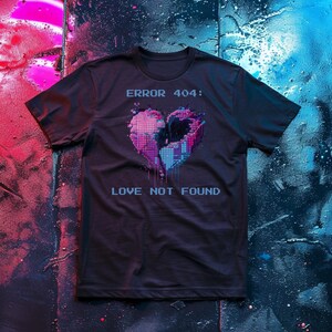 Op de afbeelding: Zwart t-shirt met een gepixeld hartontwerp in roze, paarse en blauwe tinten. De tekst "ERROR 404: LOVE NOT FOUND" staat boven en onder het hart in blauwe letters. Het t-shirt wordt op een donkere achtergrond getoond.