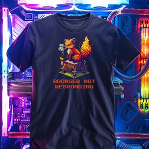 以下が含まれることがあります： ピクセル化されたキツネ、炎、煙が描かれた濃い青色のTシャツ。「BROWSER NOT RESPONDING」の文字がオレンジ色でプリントされています。クルーネックの半袖Tシャツです。