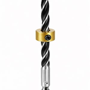 May include: A black and silver auger drill bit with a star-shaped tip. The drill bit has a gold-colored collar with a black screw. The base of the drill bit is silver.