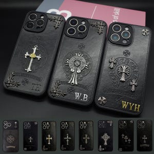 May include: Black leather phone cases with silver crosses and decorative corner details. Each case has a unique cross design and initials: TH, W.B, and WYH. The cases are designed for a smartphone.